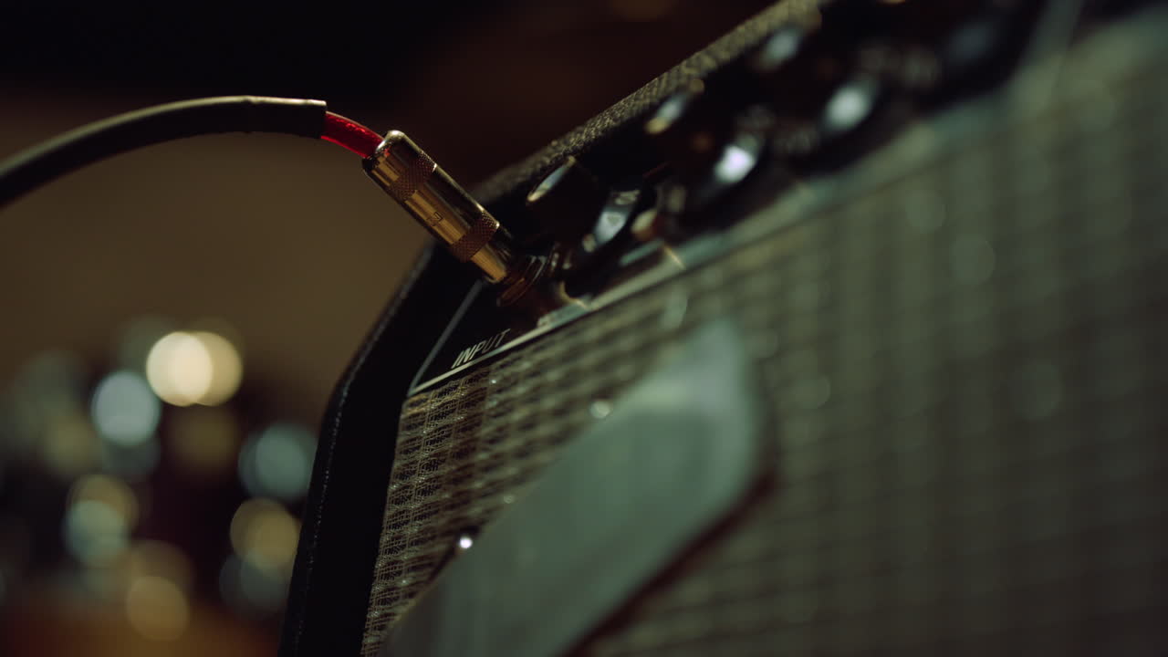 리허설 스튜디오에서 기타리스트가 증폭기를 연결합니다.