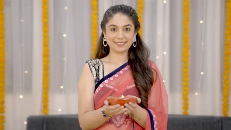 mujer india sosteniendo una lámpara de barro encendida