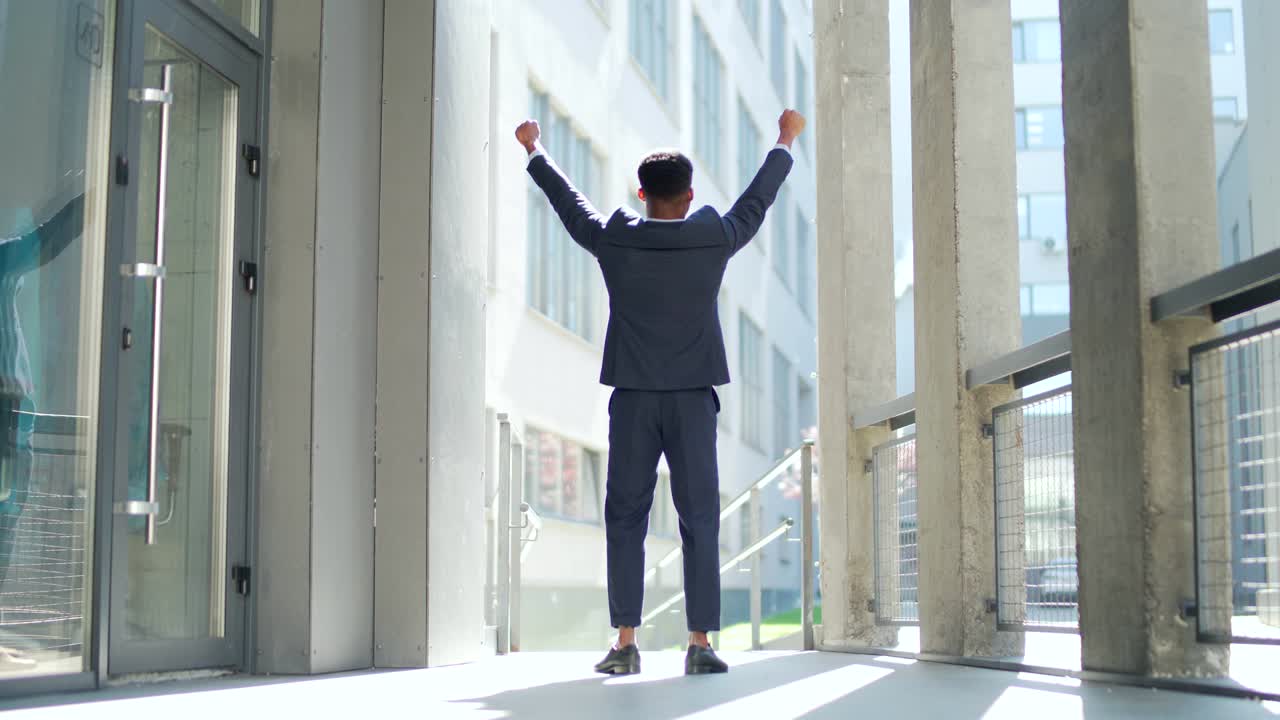 un exitoso hombre de negocios afroamericano con los brazos en alto celebrando la victoria. concepto: éxito, crecimiento profesional, victoria, libertad.