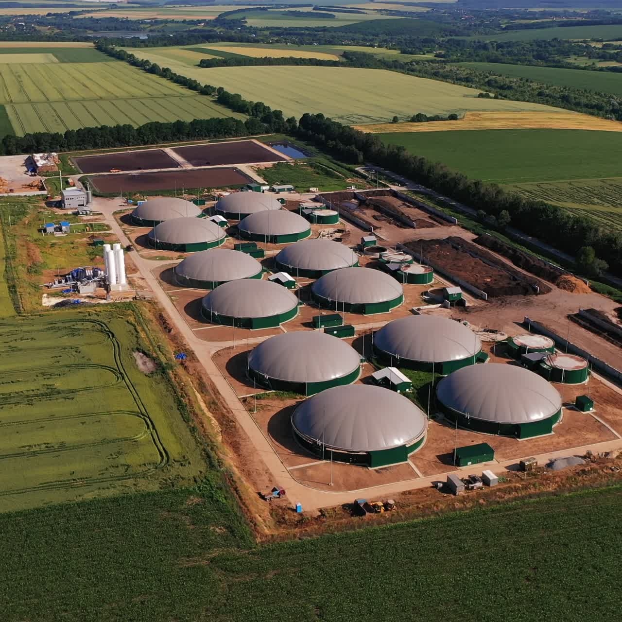 Neoteric agricultural biogas plant producing save energy from leftovers. Technological plant locating in the fields. Aerial view