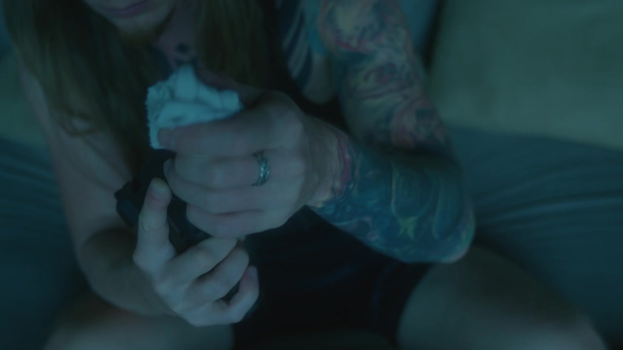 Persona limpiando y manteniendo una pistola con un paño