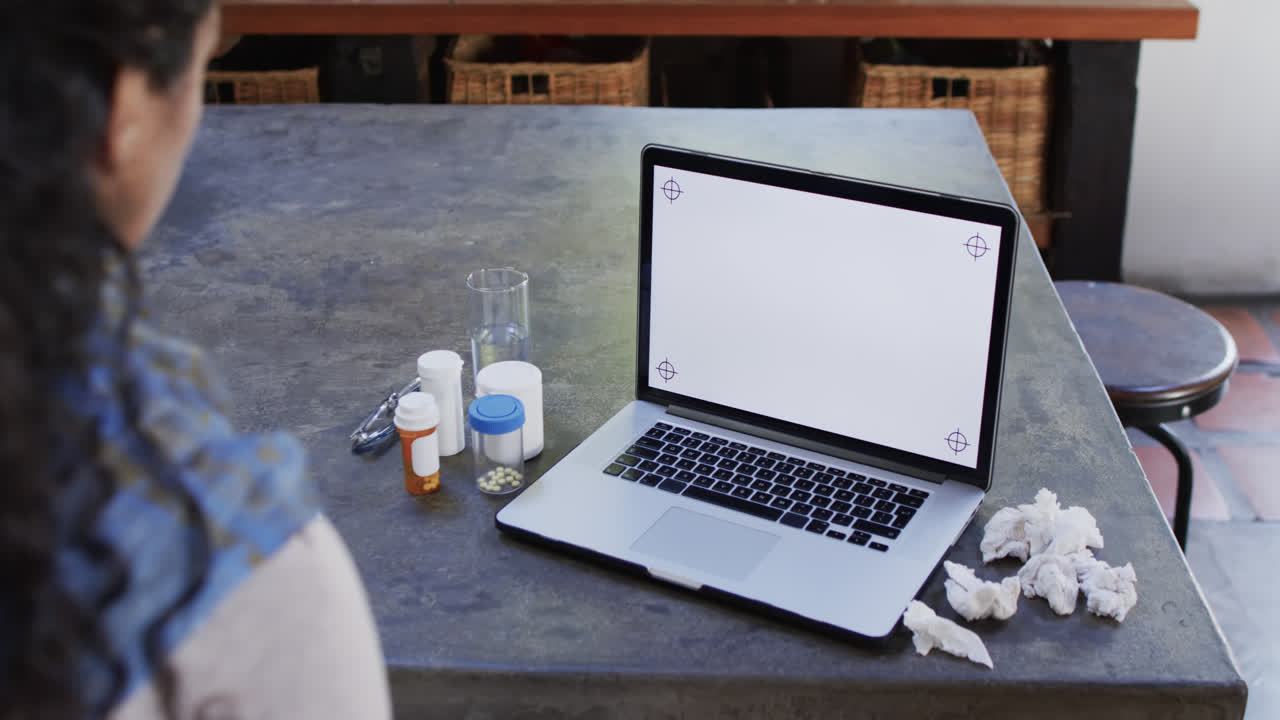 mujer biracial con frío haciendo una llamada de video usando una computadora portátil con espacio de copia en casa, cámara lenta