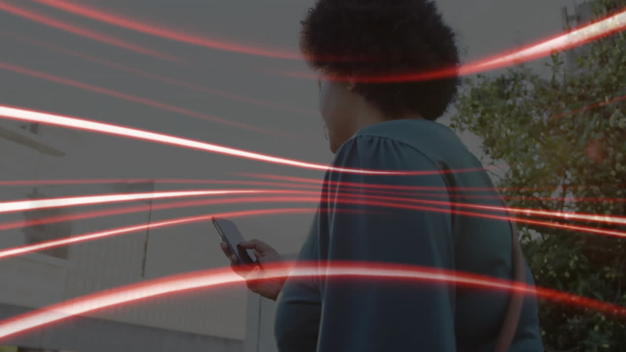 Woman holding smartphone outdoors in marketing technology scene, showing red animated data streaks