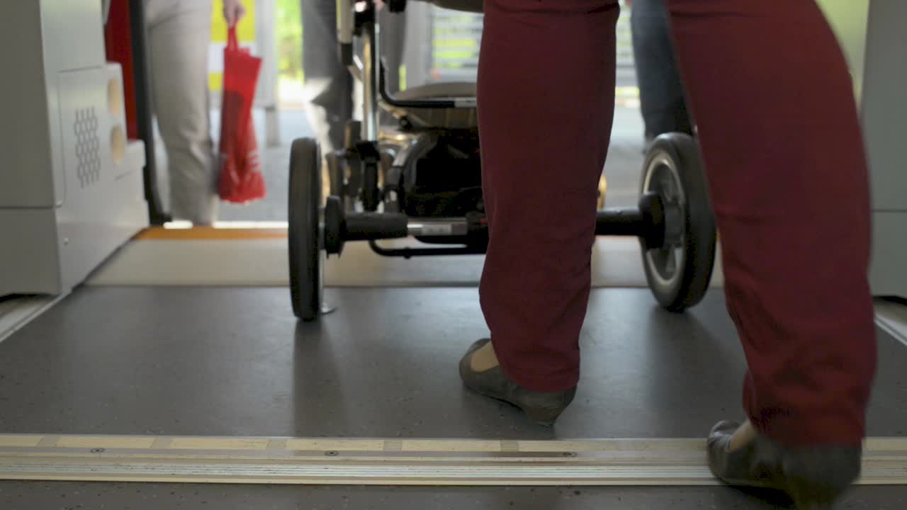 Woman with stroller exits a train onto the platform in a close-up shot of her legs and wheels