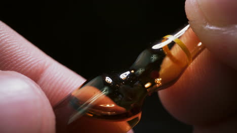 lab assistant holds brown glass ampule with new vaccine