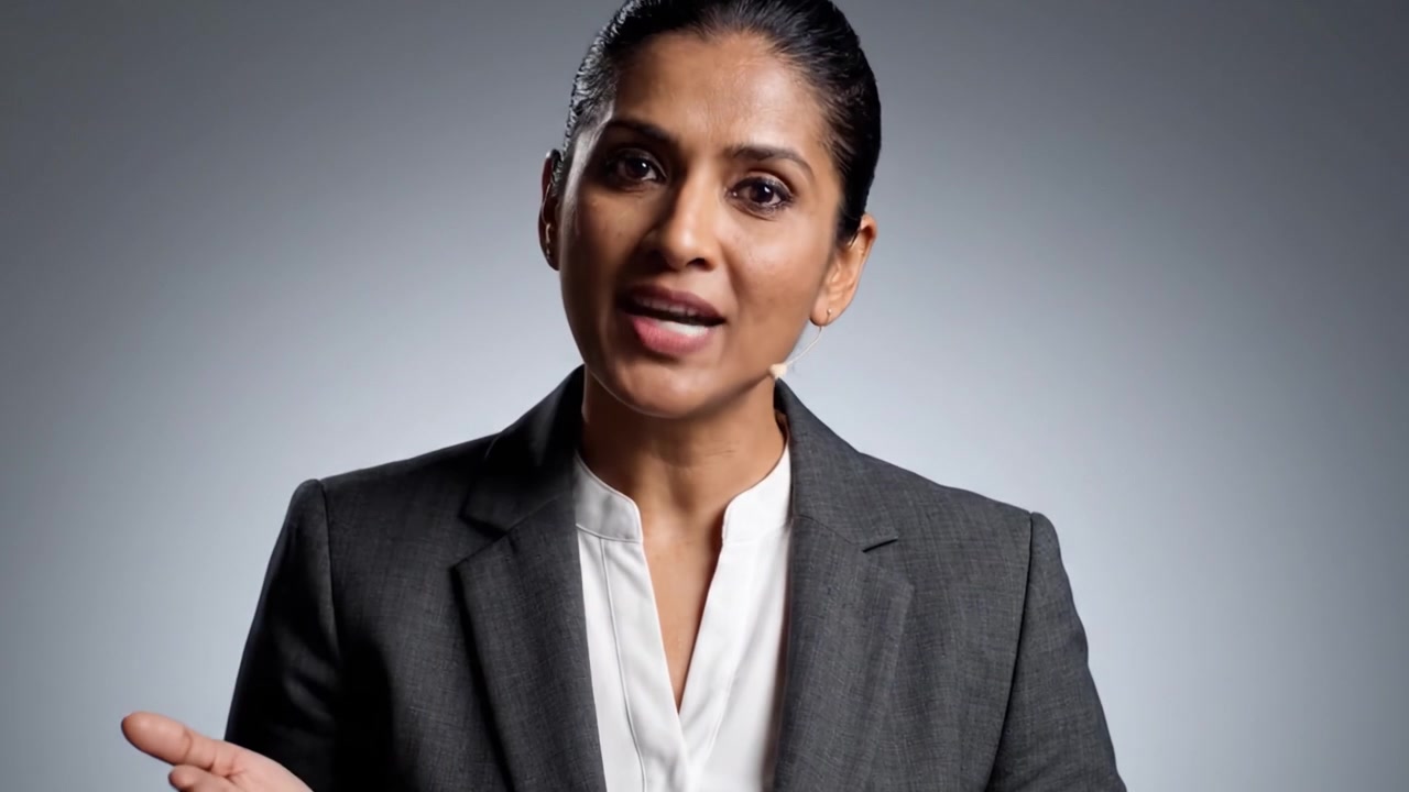 A confident woman in a business suit conveys an engaging message, showcasing her expertise and charisma during a presentation with a professional demeanor.