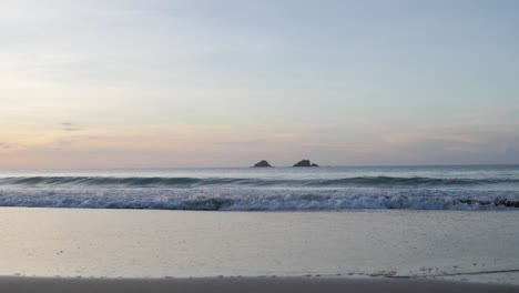 ultra slow motion shot of waves breaking and swashing at sandy beach with beautiful colourful sky at dusk in asia