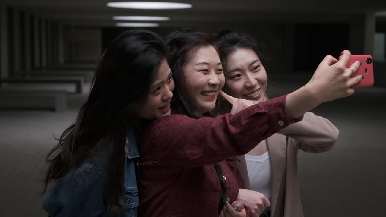 Portrait of a group of asian women friends taking a selfie with a mobile phone together.