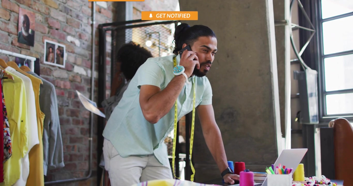 Stilista al telefono in uno studio creativo con notifiche dei social media.