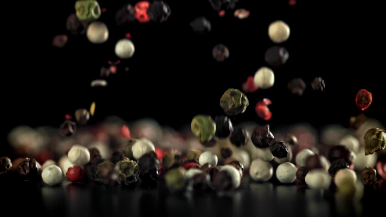 Mixed Peppercorns Falling in Slow Motion on Black Background
