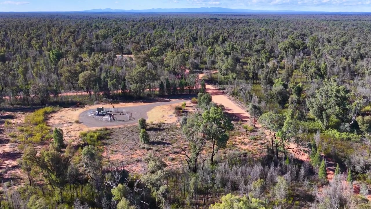 Pemandangan udara mendekati area terbuka dengan bantalan sumur ekstraksi gas di semak belukar Australia