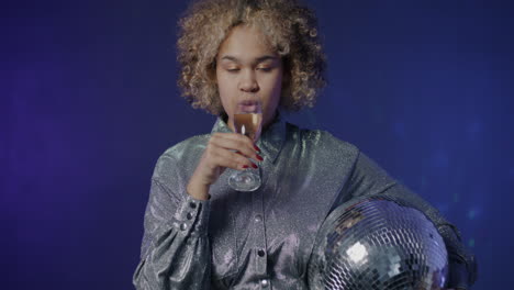 woman celebrating with champagne and disco ball