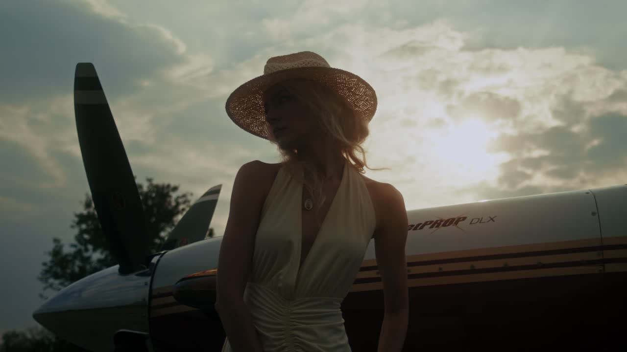 Woman in a straw hat near a small plane