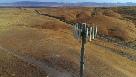 4k drone footage orbiting around a cellular tower with golden hills and blue skies