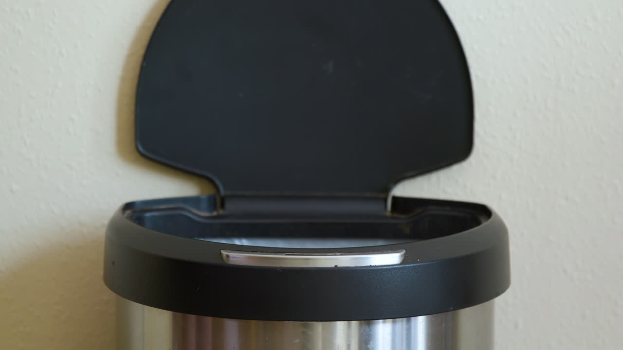 Uomo getta un cartone del latte in una pattumiera automatica con sensore di movimento - Primo piano.