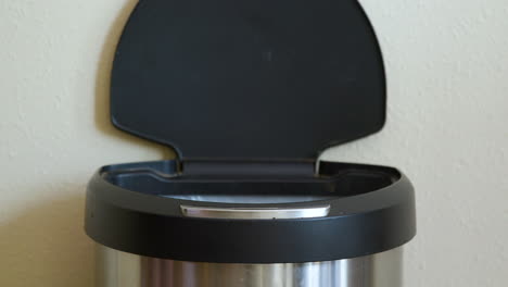 man throws away milk jug in motion sensing touchless trash can - close-up