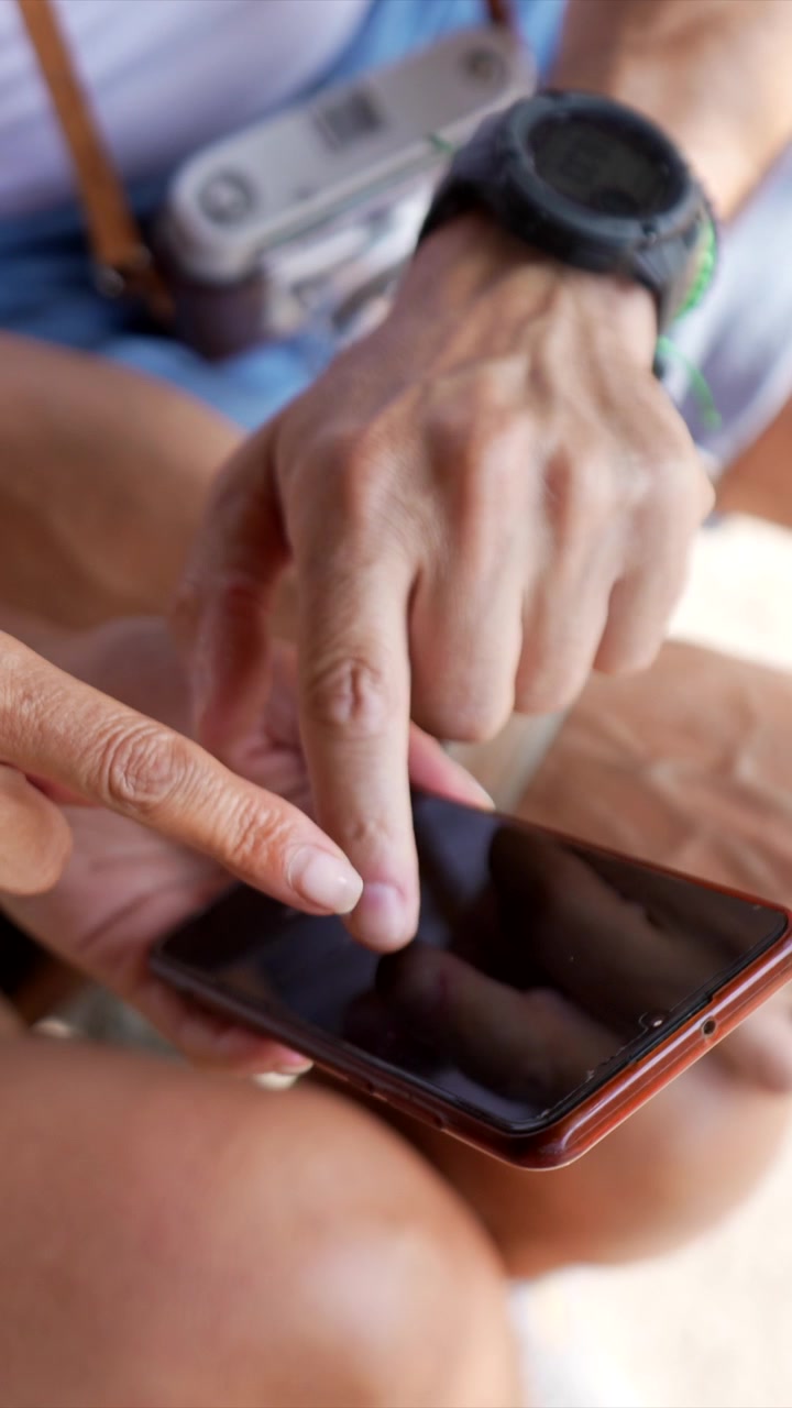 Due persone che usano uno smartphone insieme all'aperto.
