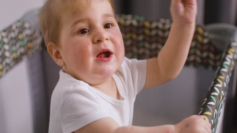 Top-View-Of-Baby-In-White-Bodysuit-Eating-A-Fruit-Inside-The-Baby-Playground