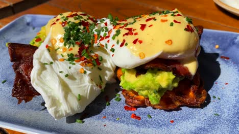 Leckeres-Eier-Benedict-Frühstücksgericht-Mit-Knusprigem-Speck,-Sauce-Hollandaise-Und-Avocado-Auf-Süßkartoffel-Rösti,-Pochierte-Eier-Zum-Brunch-In-Einem-Restaurant,-4K-Aufnahme