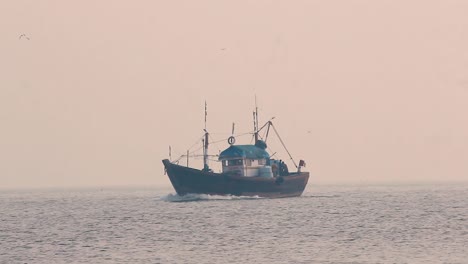 Un-Pequeño-Barco-De-Pescadores-Navegando-En-Medio-Del-Océano-Durante-La-Puesta-De-Sol-Con-Pequeñas-Olas-Tranquilas-Y-Regresando-A-Casa-En-Un-Fondo-De-Video-De-Clima-Brumoso-En-Mov-En-Full-Hd