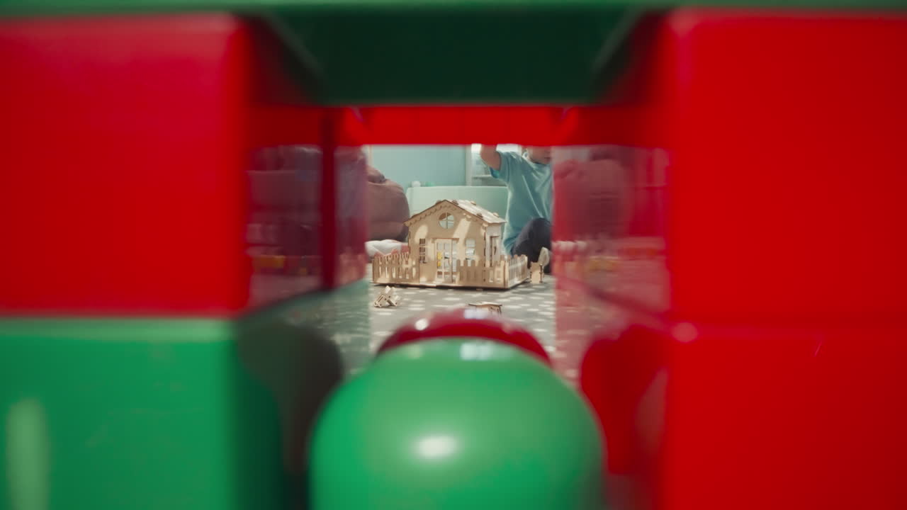 el chico rubio enfocado construye una pared de bloques multicolores