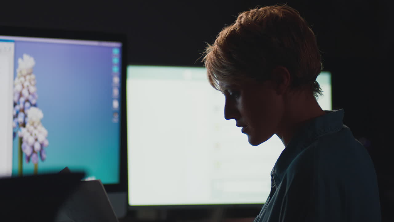 Businesswoman Working Late In Office With Face Lit By Computer Screen