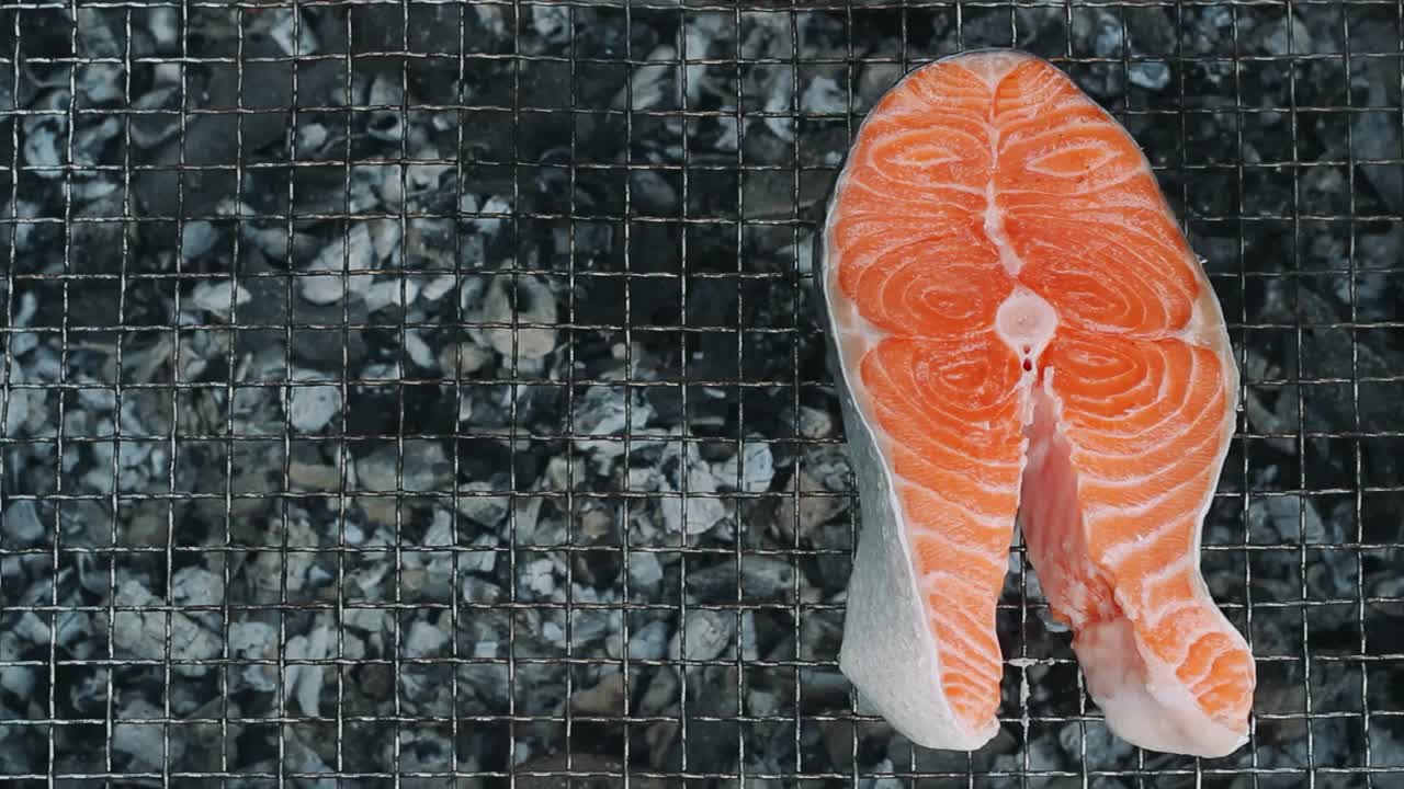 Bistecca di salmone che cuoce sulla griglia a carbone. Primo piano: cottura di filetto di salmone sulla griglia.