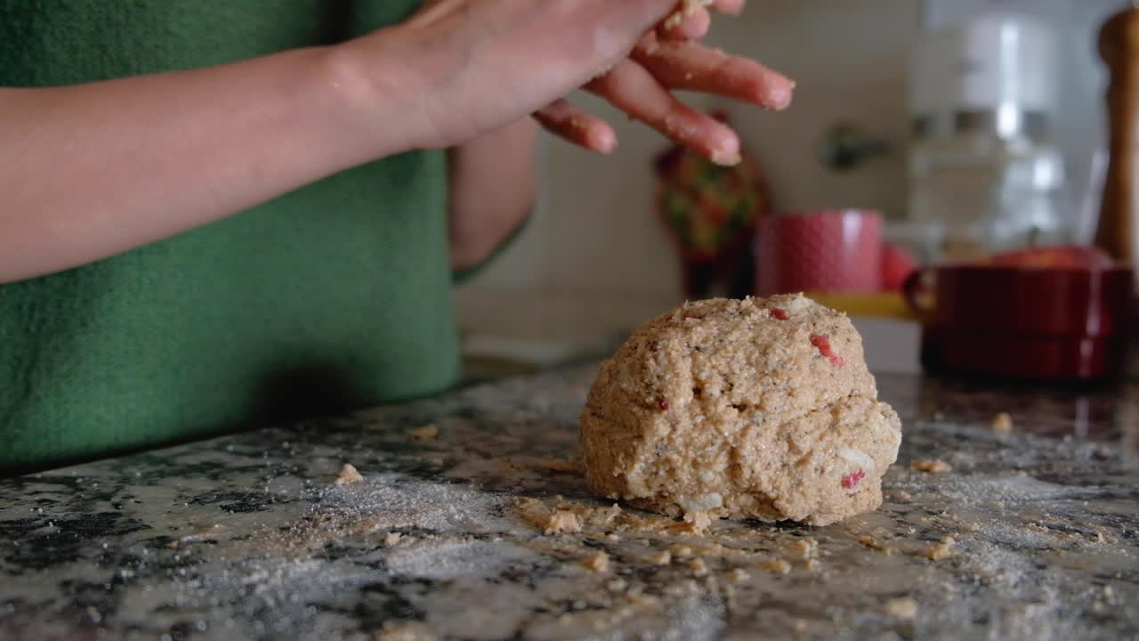 Woman hands putting together ball of dough and wiping it from her fingers