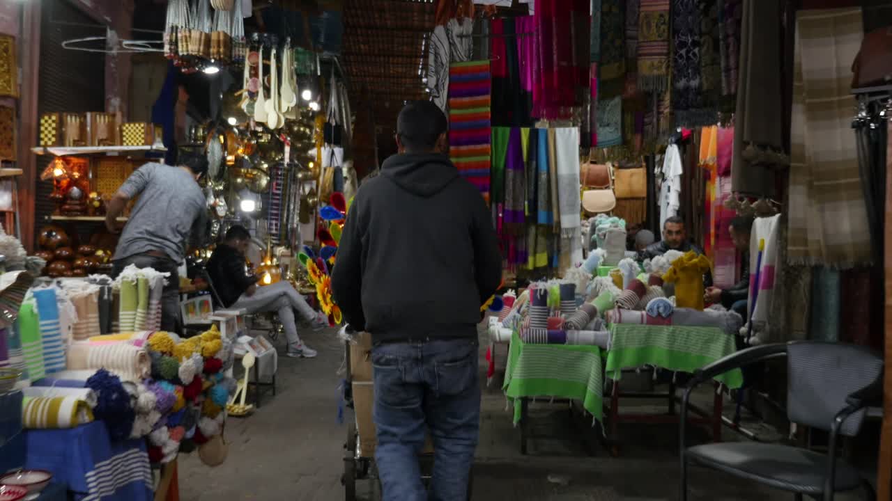 4k smooth, gimbal tracking shot of man pushing colourful trolley through the Medina of Marrakech.