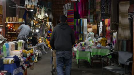 4k smooth, gimbal tracking shot of man pushing colourful trolley through the medina of marrakech.