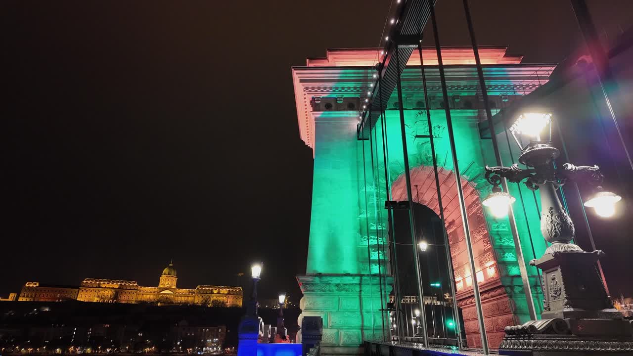 Danube night pan from lit up Chain Bridge stone tower to Buda Castle