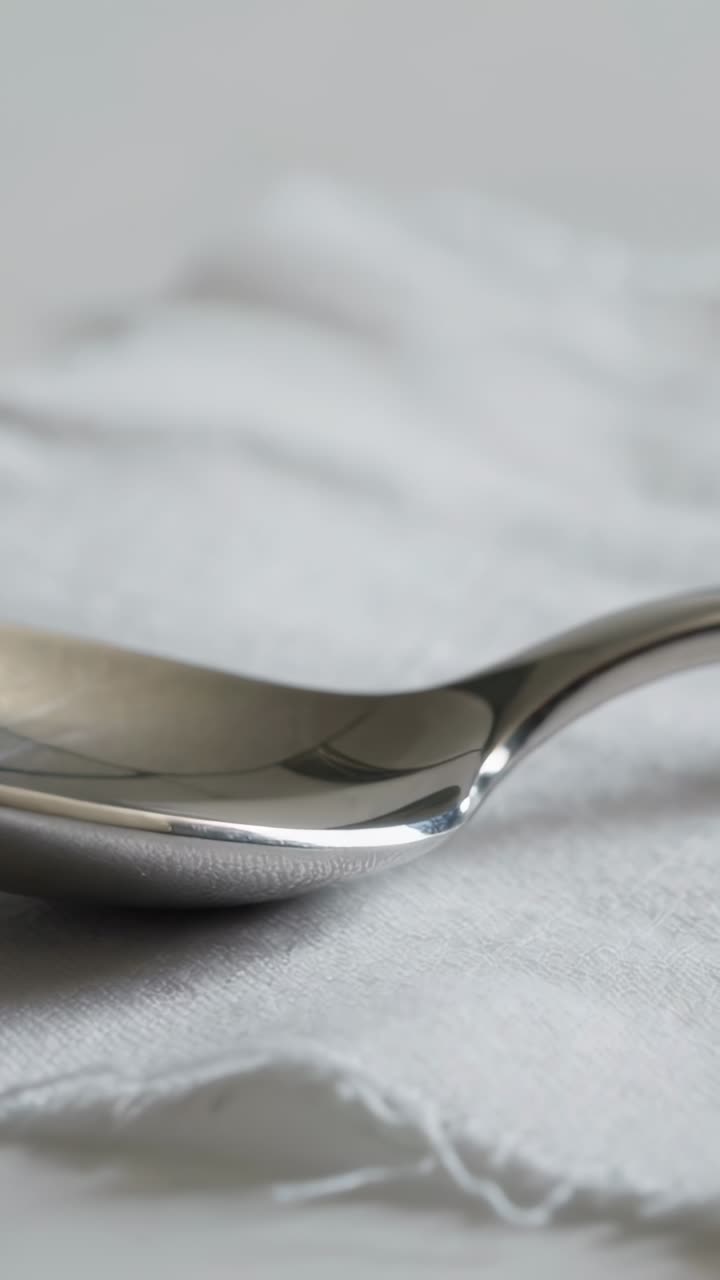 Close-up of a Shiny Silver Spoon on White Fabric