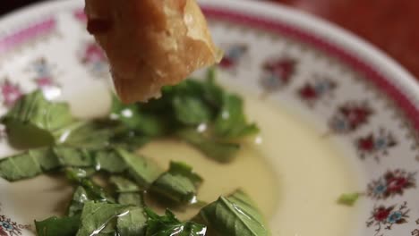 slow motion close up of a piece of lumpia or fried springroll dipped in vinegar and herbs condiment showing a traditional local filipino food culture