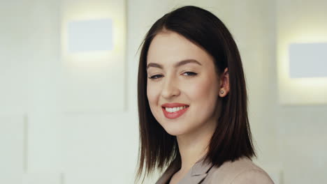 close-up view young caucasian businesswoman in jacket looking at the camera and smiling in a meeting room