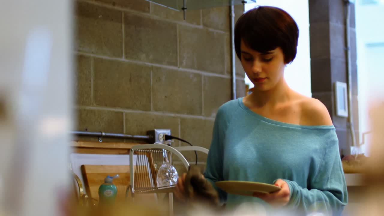 mujer limpiando un plato en la cocina