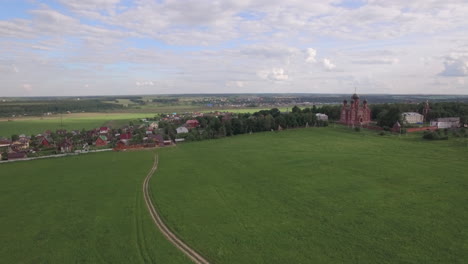 flying over green meadows and lukino village in russia