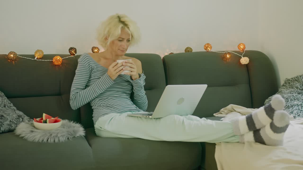 Kvinde slapper af på sofaen med bærbar computer