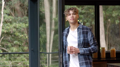 young man holding coffee mug, gazing outside, enjoying peaceful morning at home
