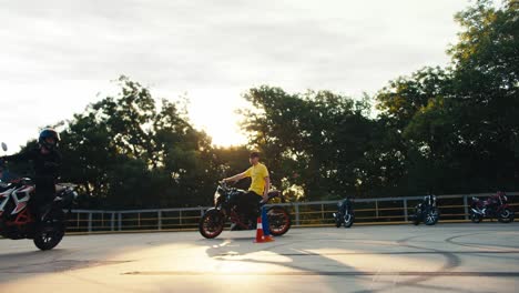 filming of a biker instructor and a biker student in a driving school. learning to drive a motorcycle at a motorcycle school