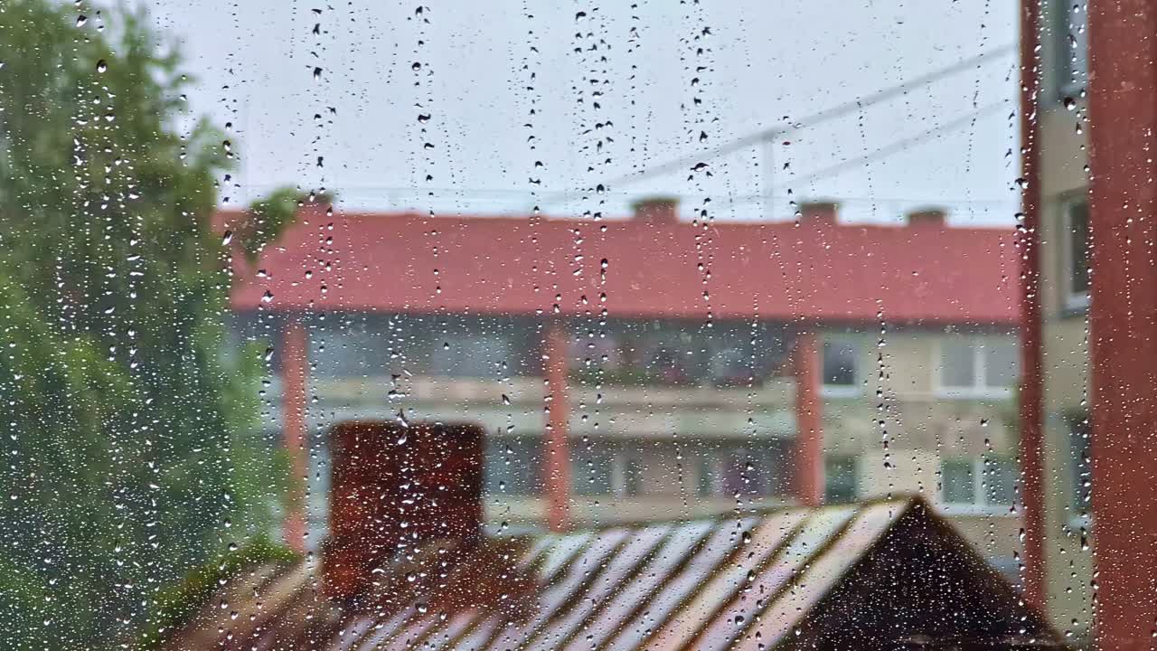 Rain Dripping Down Windowpane With Apartment Buildings in Blurred Background