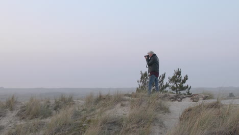 close up shot of a landscape photographer man taking photos in nature at sunset or sunrise