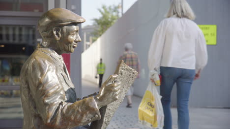 profile view of bronze sculpture of man sitting down reading newspaper in oslo