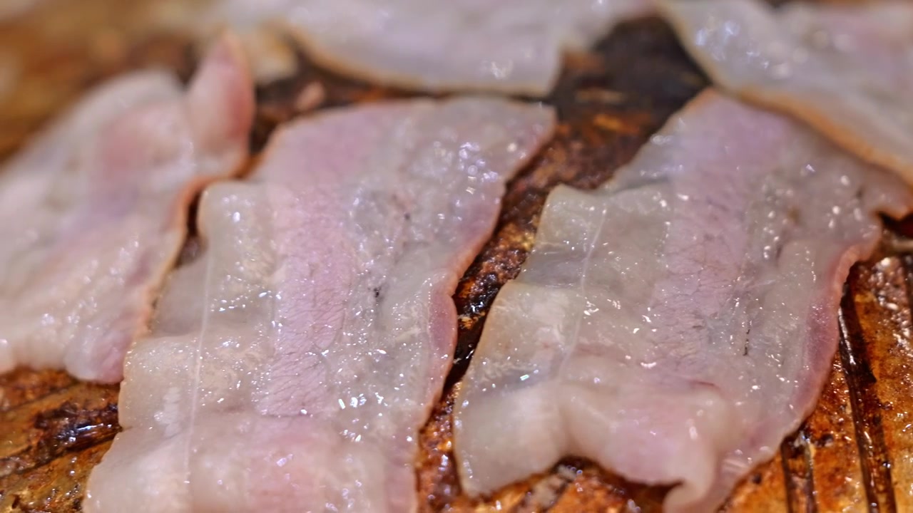 Fatias de bacon cru e carne de barriga de porco numa tábua de madeira com marmoreado e textura