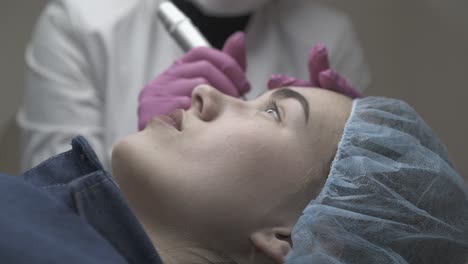 skilled beautician in sterile gloves colours patient eyebrow