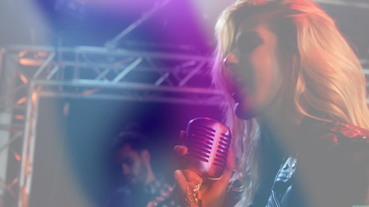 female vocalist performing on music stage, with equalizer rising around mic under colored lights