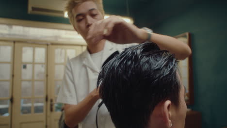barber blow drying hair of client in the barbershop