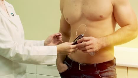 médico con una bomba de insulina conectada en el abdomen del paciente y sosteniendo la bomba de insulina en sus manos. concepto de diabetes.