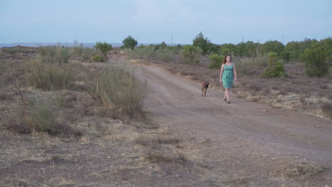Woman walking with dog on a dirt path
