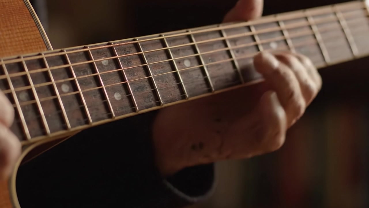 Una visione intima delle mani di un chitarrista mentre navigano abilmente le corde, catturando l'essenza della creazione musicale e dell'espressione emotiva in ogni nota suonata.