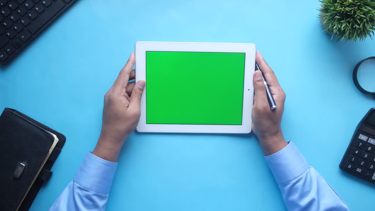 persona que sostiene una tableta con una pantalla verde